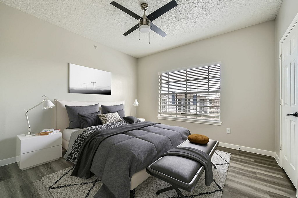 A bedroom with a bed, chair, and a ceiling fan.