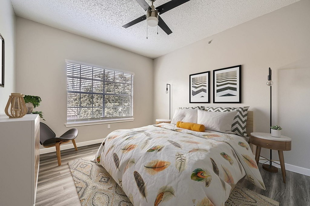 A bedroom with a bed, chair, and a ceiling fan.