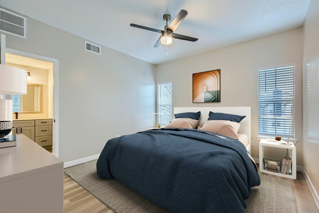 A bedroom with a bed, nightstand, and a ceiling fan.