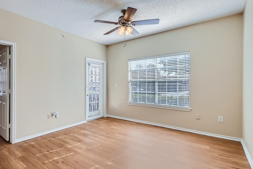 A room with a ceiling fan and a window with blinds.