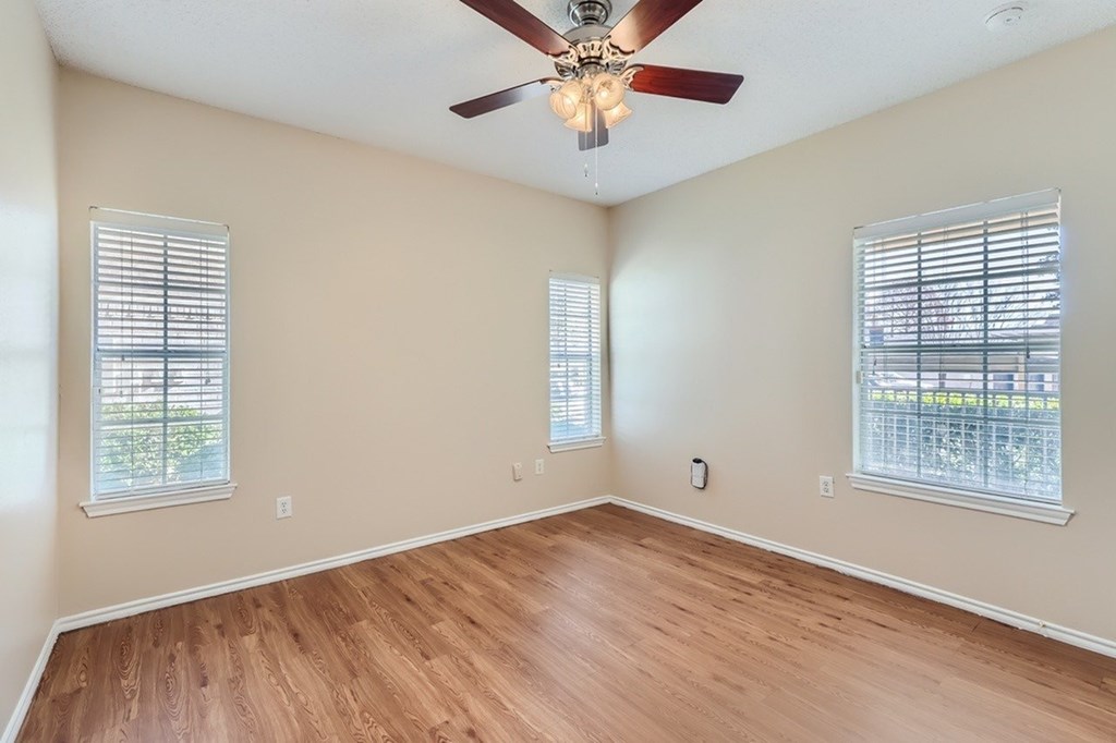 A room with a ceiling fan and two windows.