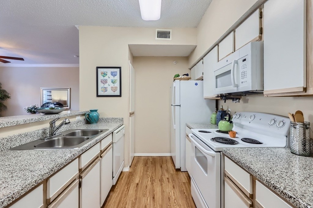 A kitchen with white appliances and granite countertops.