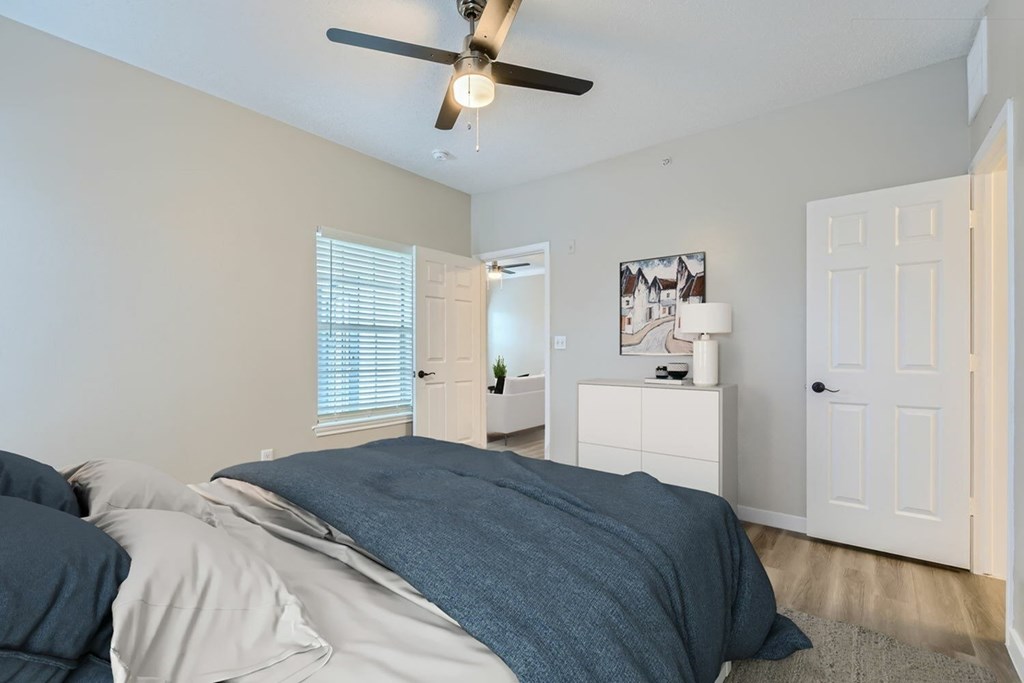 A bedroom with a bed, dresser, and a ceiling fan.
