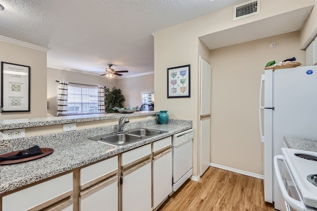 A kitchen with a white fridge and a white sink.