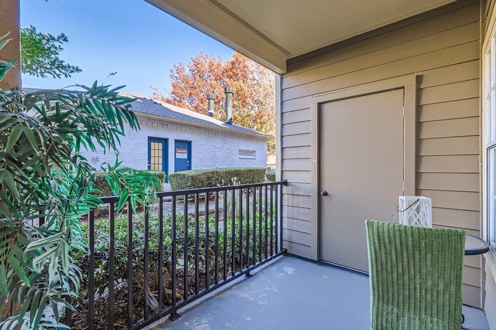 A balcony with a green chair and a railing.