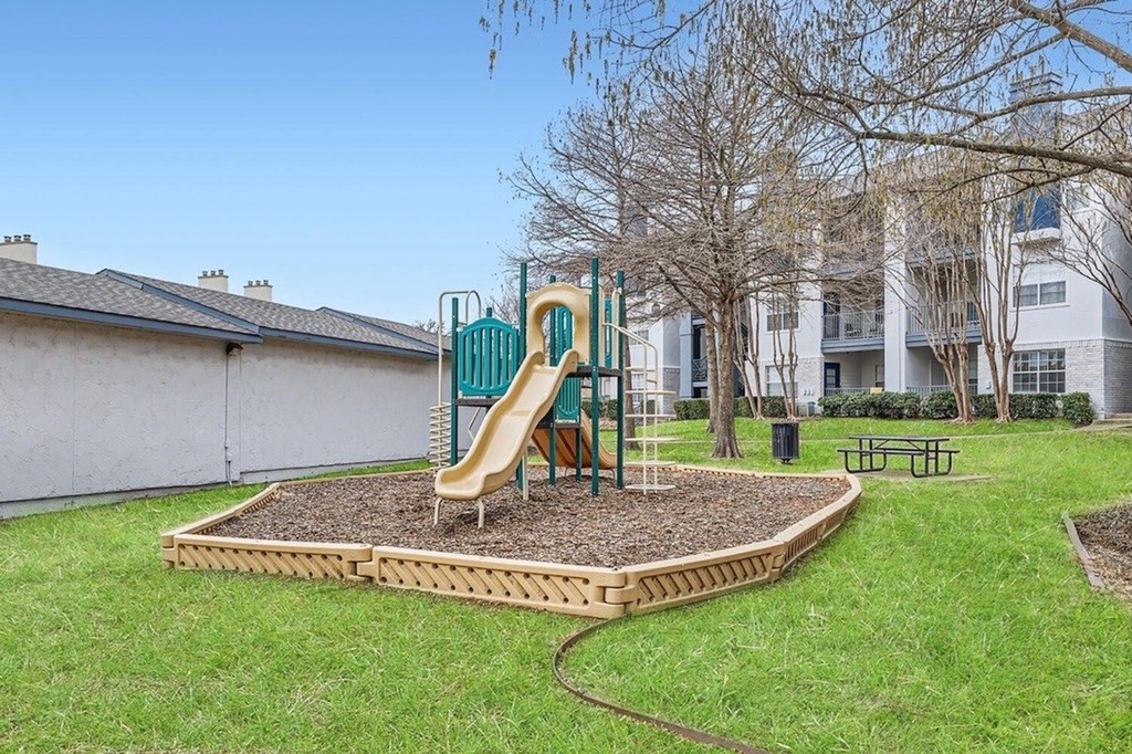 A playground with a yellow slide and a green slide.