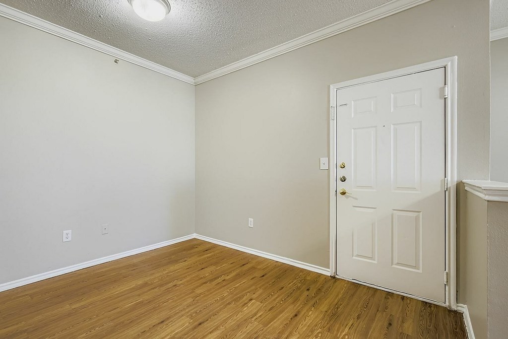 A room with a white door and wooden floor.