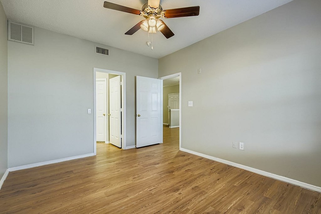 A room with a ceiling fan and wooden floors.