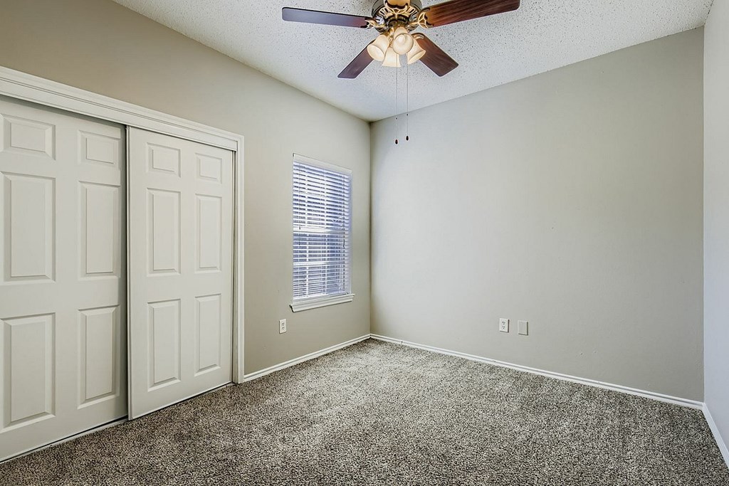 A room with a ceiling fan and a window with blinds.