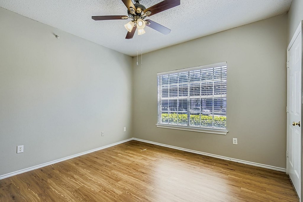 A room with a ceiling fan and a window with blinds.