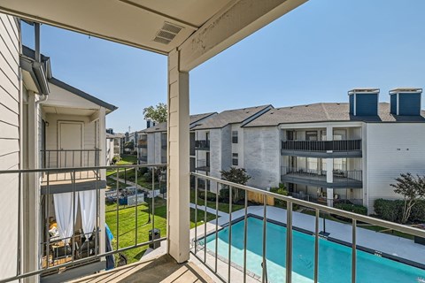 A balcony with a pool and a view of apartment buildings.