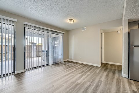 A spacious room with a sliding glass door and a wooden floor.