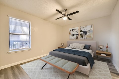A bedroom with a bed, a ceiling fan, and a window with blinds.