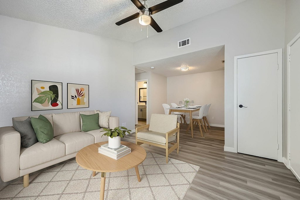 A living room with a couch, coffee table, and a dining area in the background.