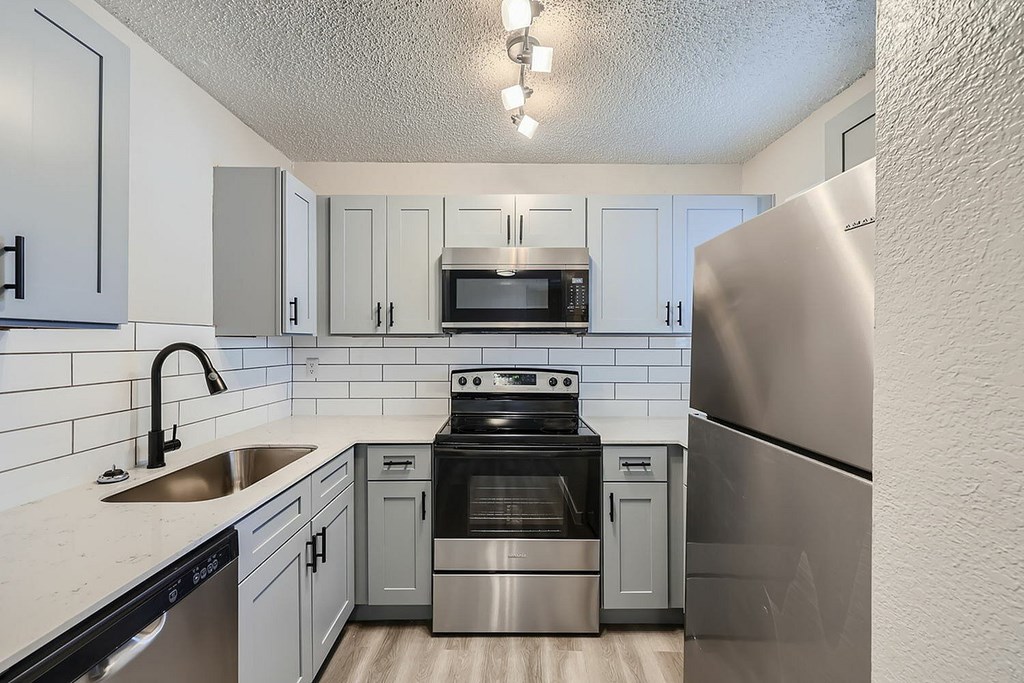 A kitchen with a stove, sink, and refrigerator.