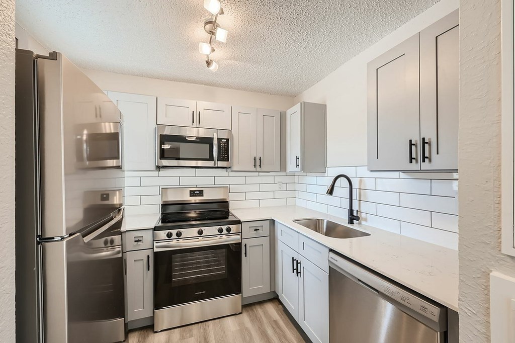 A kitchen with stainless steel appliances and white cabinets.
