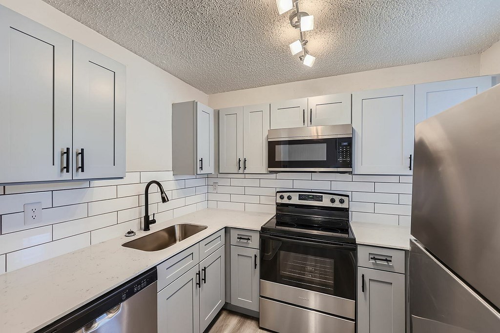 A kitchen with white cabinets and a stainless steel refrigerator.