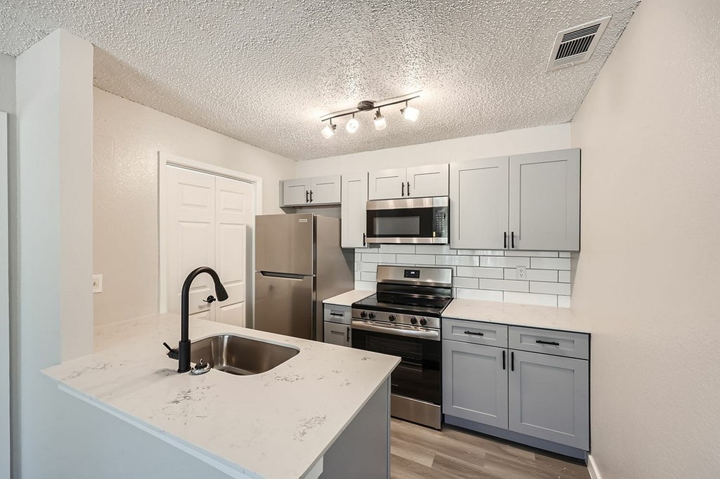 A kitchen with a sink, stove, and refrigerator.