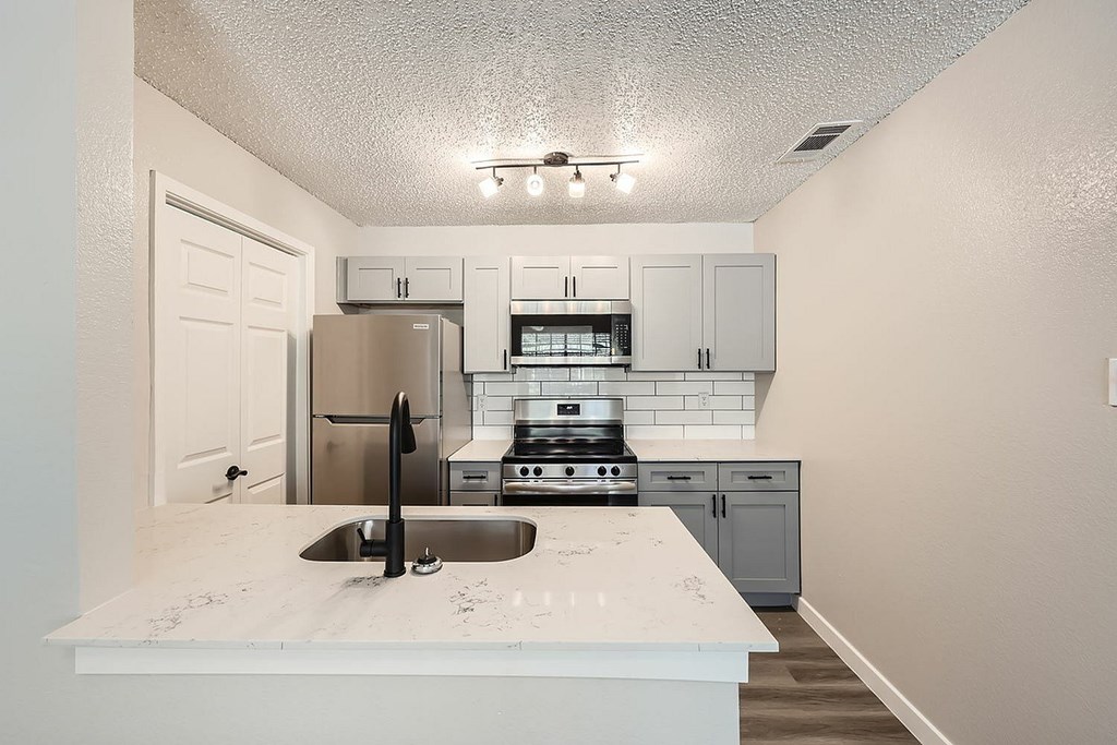 A kitchen with a white counter top and stainless steel appliances.