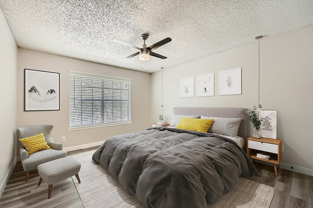 A bedroom with a bed, chair, and pictures on the wall.
