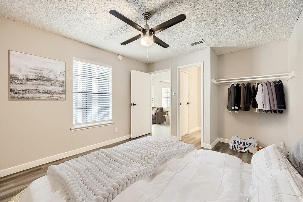 A bedroom with a large bed and a ceiling fan.