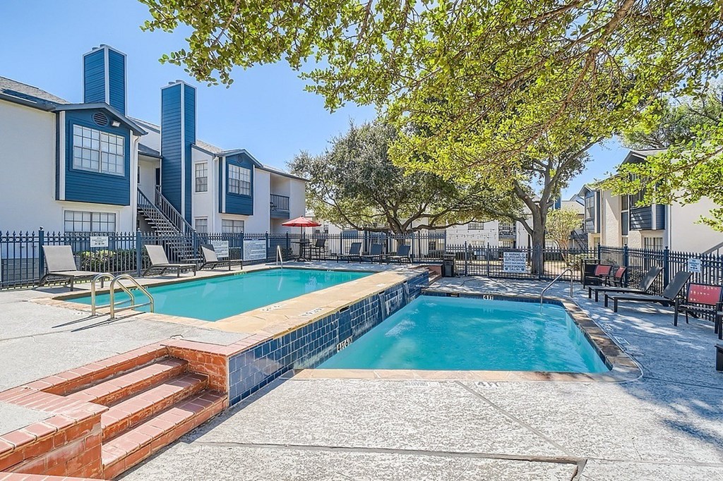 A swimming pool surrounded by a fence and trees.