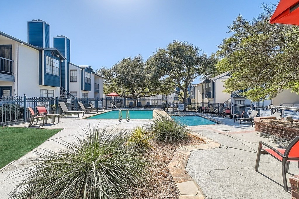 A pool surrounded by trees and chairs.
