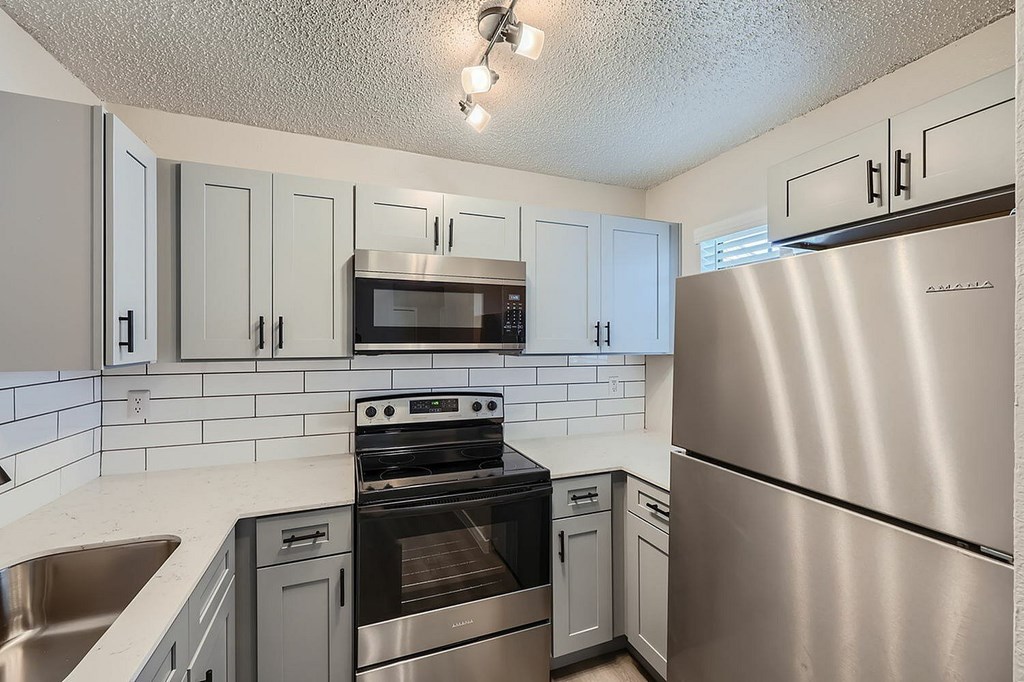 A kitchen with a stainless steel refrigerator, oven, and microwave.