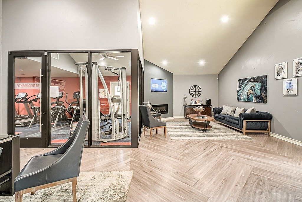 A living room with a grey couch and a television on the wall.