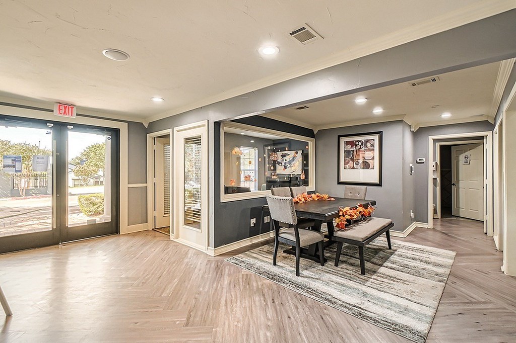 A dining room with a table set for two and a view of the outdoors through the sliding glass doors.