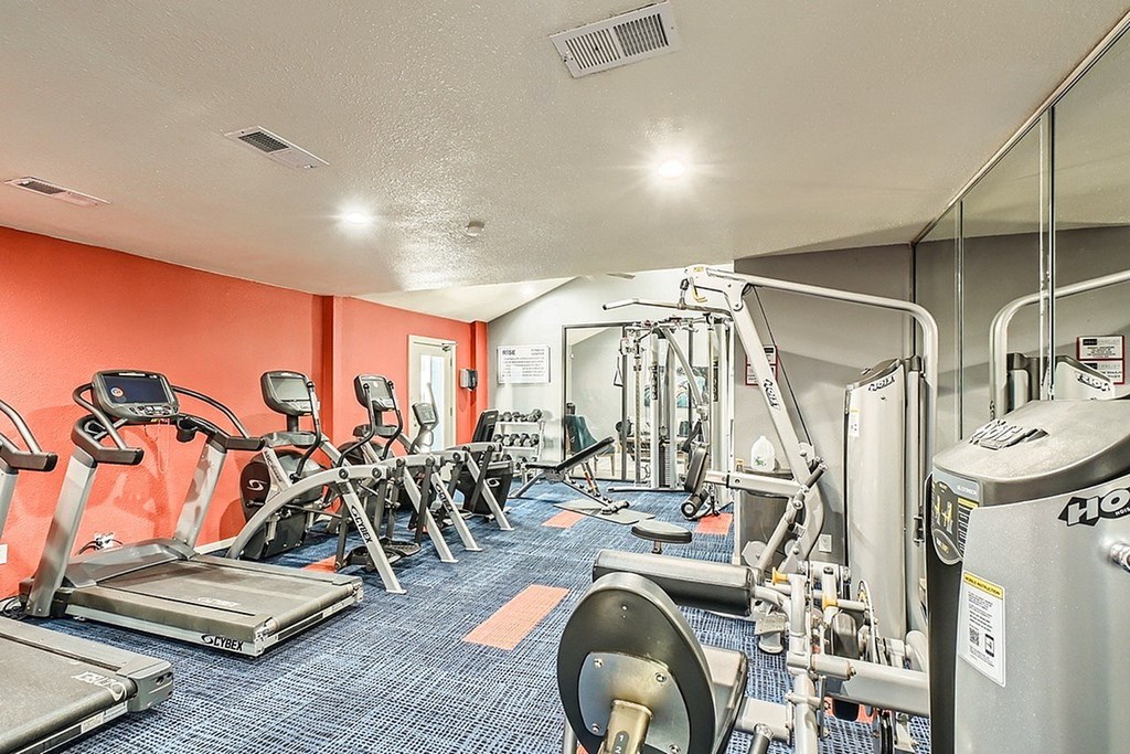 A gym with a variety of equipment including treadmills, weights, and exercise machines.