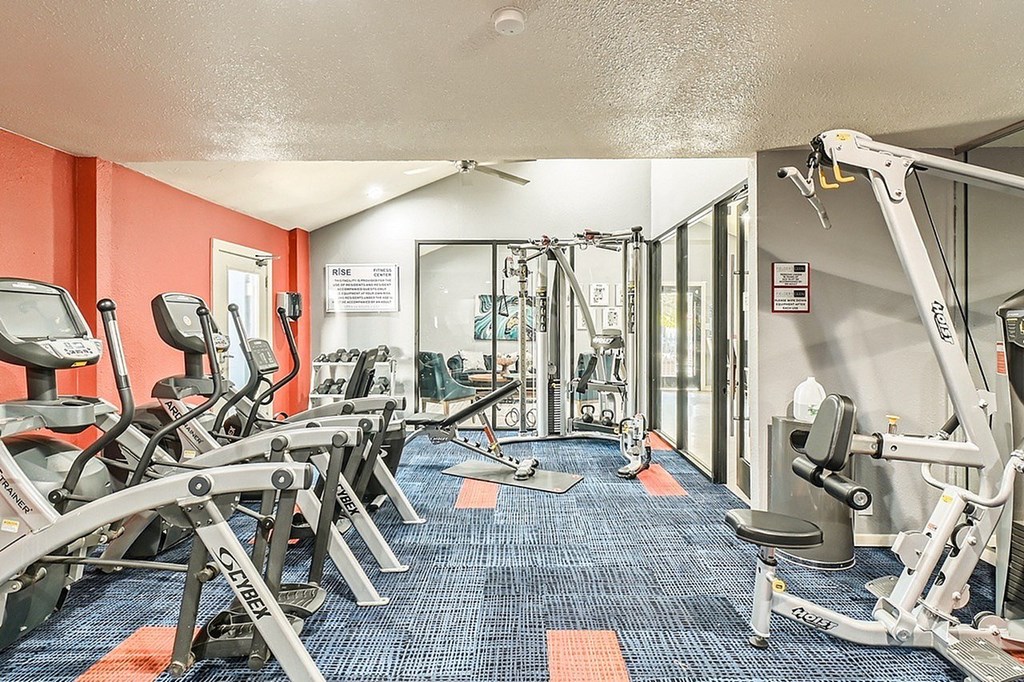 A gym with a variety of equipment including treadmills, weights, and exercise machines.