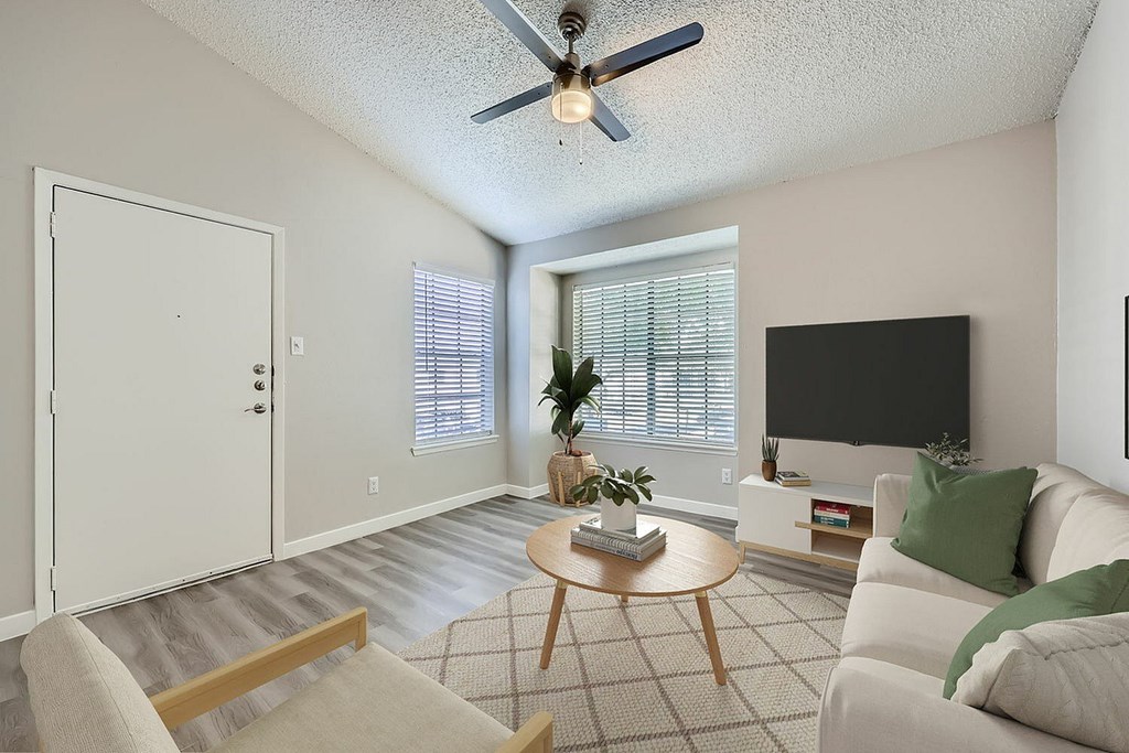 A living room with a ceiling fan, a couch, a chair, a coffee table, and a flat screen TV.