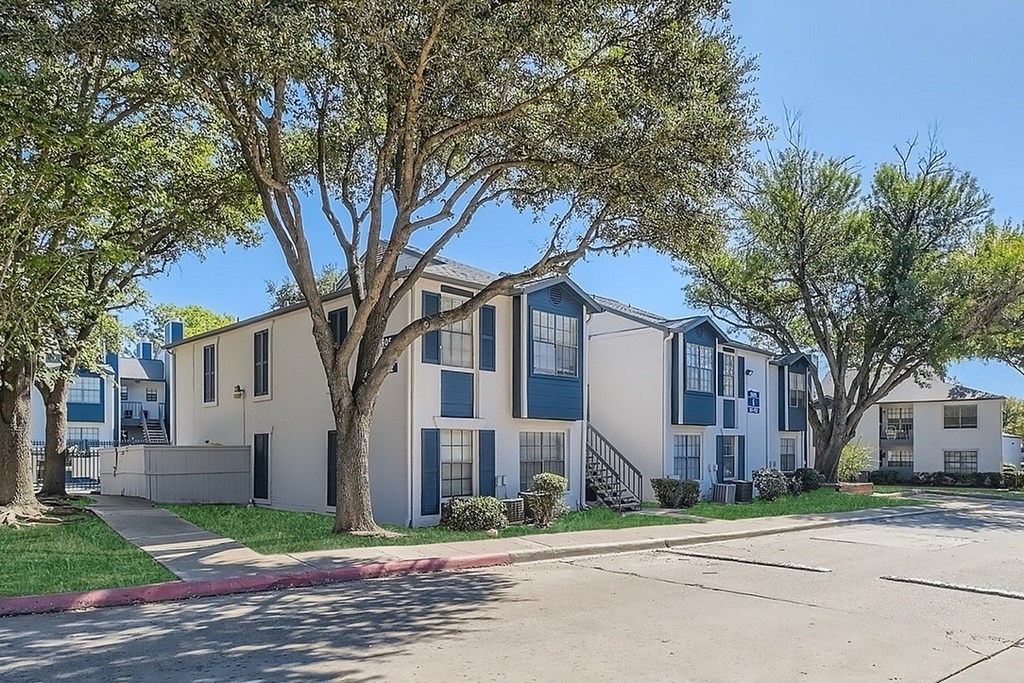 A tree in front of a building with a blue sky in the background.