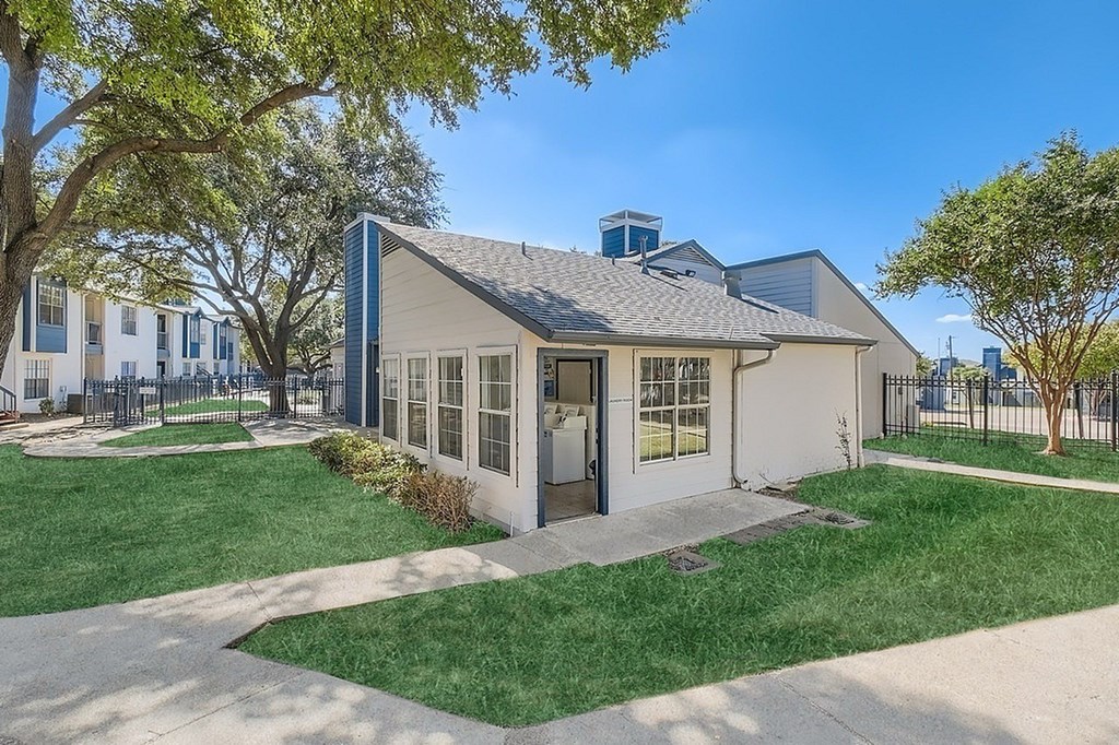A small house with a grey roof and a black fence.