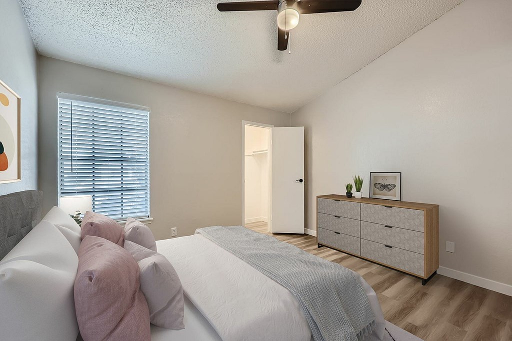 A bedroom with a bed, dresser, and window.