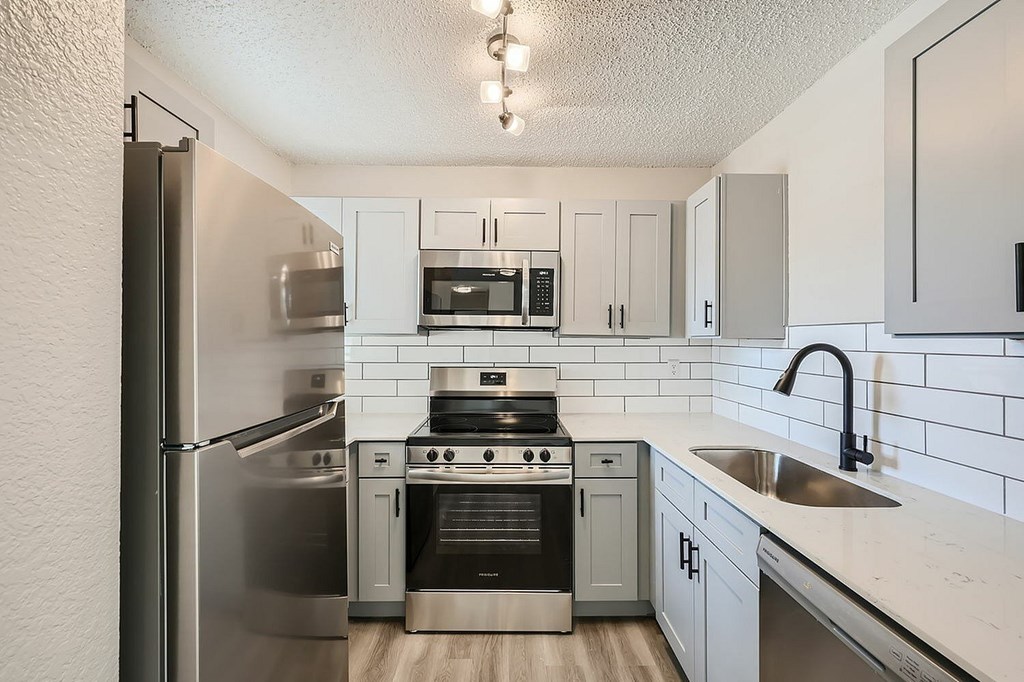 A kitchen with a stainless steel refrigerator and a white countertop.
