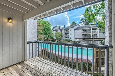 A balcony with a pool in the background.