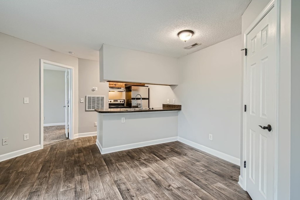 A kitchen area with a bar counter and a door leading to another room.
