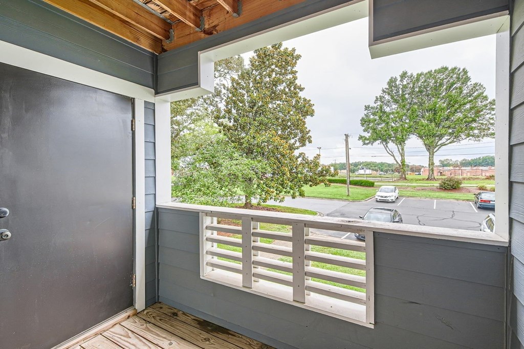 A balcony with a view of a parking lot and trees.
