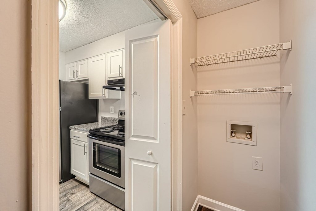 A kitchen with a black fridge and stove top oven.