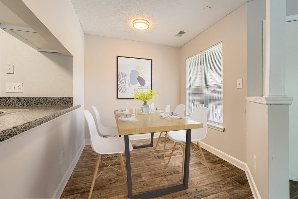 A dining room with a table set for two and a painting on the wall.