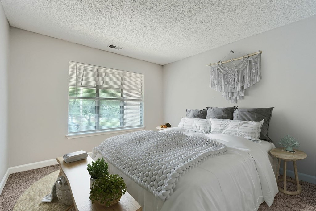 A bedroom with a bed, nightstand, and window.