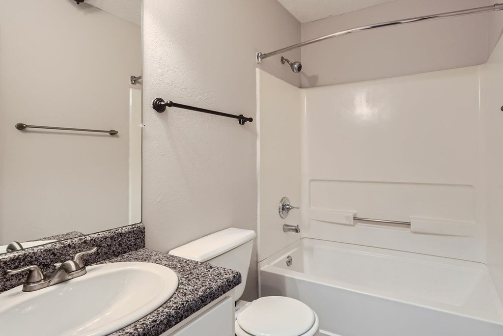 A white bathroom with a toilet, sink, and bathtub.