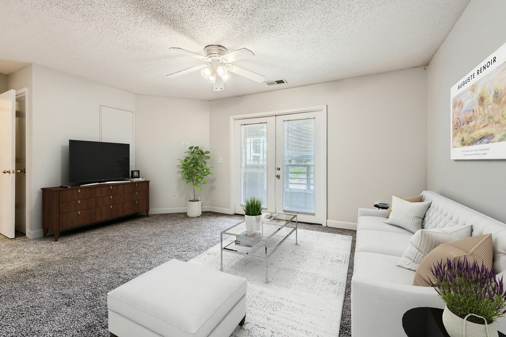 A living room with a flat screen TV, a white sofa, and a coffee table.