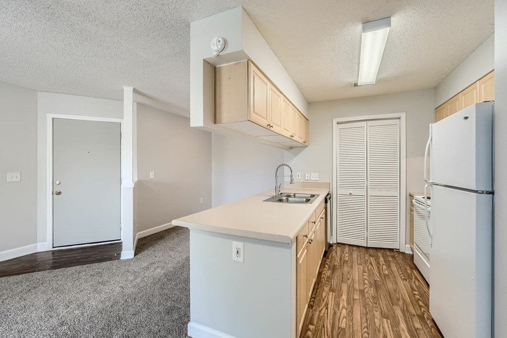 A kitchen with white appliances and wooden floors.