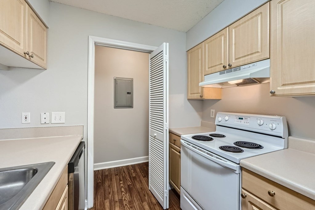 A small kitchen with a white stove and wooden cabinets.