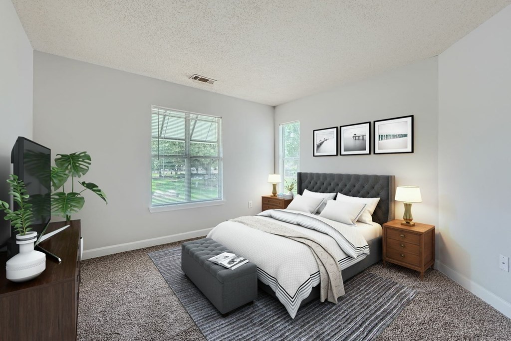 A bedroom with a large bed, a nightstand, and a plant.