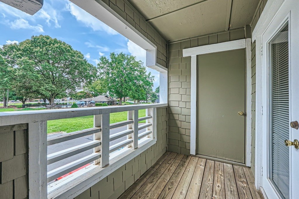 A view from a balcony with a wooden floor and a white door.
