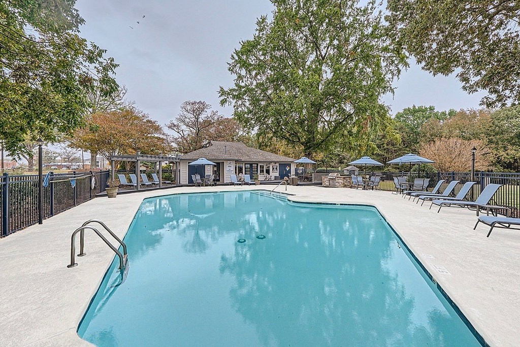 A large swimming pool surrounded by trees and lounge chairs.
